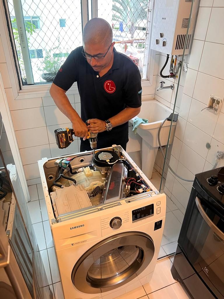 Marcelo, fundador da Tecmarc, consertando uma lava e seca Samsung na casa de um cliente